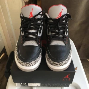 Nike Air Jordans med elefantmönster - Snygga Nike Air Jordans i svart och grått med elefantmönster. Skorna har röda detaljer och klassisk snörning. Perfekta för dig som vill ha en stilren och sportig look.