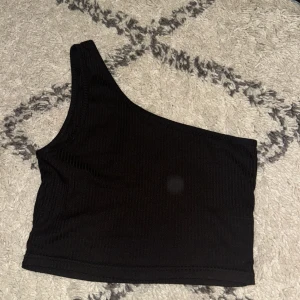 Svart oneshoulder topp - Snygg svart oneshoulder topp i ribbat material. Köpt på Shein, använt 2 gånger hemma.