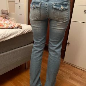 True religion Billie mid rise straight - Snygga blå jeans med klassisk femficksdesign och dekorativa knappar på bakfickorna. Midjemått 37/38 cm och innerbenslängd 83/84. De är för långa på mig som är 164(på bilden står jag på tå)