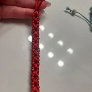  Nyckel accessoar - Säljer två unika accessoarer som man ex kan hänga på sin nyckelknippa. Den röda är handgjord och ska föreställa flätade blommor samt en guldfärgad krona som hänge. 
