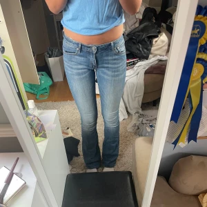 Blå bootcut jeans - Säljer ett par klassiska blå Crocker jeans med en snygg bootcut-stil. De är midwaist och har en bekväm passform. Perfekta för en avslappnad look. Jag är 175cm.