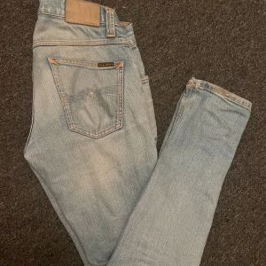 Nudie jeans grim tim - Ett par asfeta ljusblåa nudie jeans i storlek 29/32. Jeansen är i bra skick men har några få tecken på användning, kom privat för mer info! Mvh