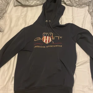 Mörkblå hoodie från GANT - Säljer en snygg mörkblå hoodie från GANT. |Skicket är inte jätte bra lite slitage här och där och en fläck som jag ej har testat att ta bort.| säljes billigt!
