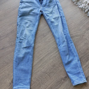 Blå skinny jeans från Lee - Säljer ett par snygga blå skinny jeans från Lee i modellen Scarlett. De är i bra skick och har en klassisk dragkedja och knapp framtill. Perfekta för både vardag och fest! Passar bra till en avslappnad stil med sneakers eller klä upp med klackar.