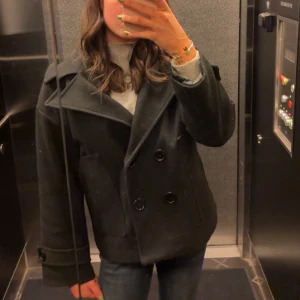 Svart kappa med stora knappar - Säljer en snygg svart kappa i mycket bra skick. Från Design By Si. 