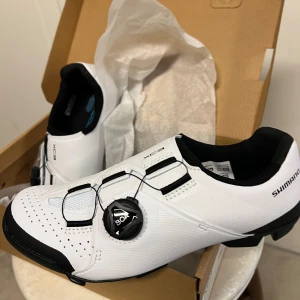 Vita cykelskor från Shimano - Helt nya och aldrig använda!! Säljer ett par vita Shimano XC3 cykelskor i nytt skick. De har en smidig BOA-snörning för perfekt passform och är designade för optimal prestanda. Perfekta för cykling med SPD-kompatibilitet. Skorna är i syntetmaterial med svarta detaljer.