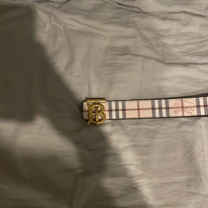 Rutig och svart bälte med guldfärgat spänne - Säljer ett burberry bälte man kan byta färg på