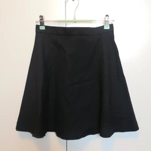 Svart A-line-kjol från Monki - Kort svart A-line kjol från Monki i strl 34. Knappt använd. Den har en dragkedja på baksidan, & fodertyget kan synas lite framtill men det är inget man tänker på, annars går det så klart att sy upp det. ***Köpare står för frakt om inget annat anges