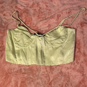 Ljusgrön korsettopp från Zara - Säljer en superfin ljusgrön korsettopp från Zara. Den har smala axelband och en snygg passform med smockdetaljer på baksidan för extra komfort. Perfekt för sommarens fester eller en utekväll. Toppen är i mycket bra skick och redo för nya äventyr! 