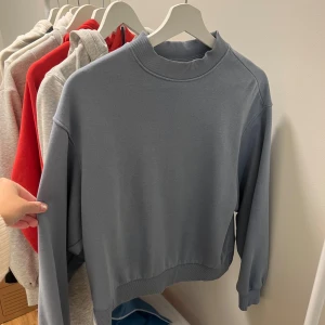 Grå sweatshirt - Säljer en stilren grå/blå sweatshirt i mycket bra skick. Den har en ribbad krage och långa ärmar, perfekt för både höst och vår. Passar till vardags eller en avslappnad dag ute. Supermjuk och bekväm!