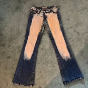 Unika lågmidjade jeans med blekta detaljer - Säljer ett par unika jeans från Casablanca med coola blekta detaljer fram och bak. De har en klassisk femficksdesign och knappgylf. Perfekta för dig som vill ha något coolt som ingen annan harl! Passar både till vardags och fest.