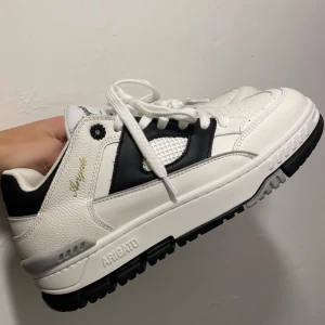 Axel Arigato Sneakers - Säljer mina fina nya Axel Arigato Area Lo sneakers. Skorna är vita med svarta detaljer. Dem är helt oanvända. Nypris: 3150kr. Storlek 40 men kan passa en 39a med inlägg