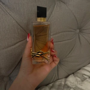 Parfym från Yves Saint Laurent - Säljer en elegant parfym från Yves Saint Laurent. Flaskan är rektangulär med en stilren svart kork och en gyllene detalj runt halsen. Den har en lyxig känsla och är perfekt för både dag och kväll. Doften är fräsch och sofistikerad, idealisk för den som vill känna sig speciell.