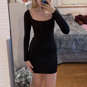 Svart bodycon-klänning - Svart tajt festklänning med snörning i ryggen!