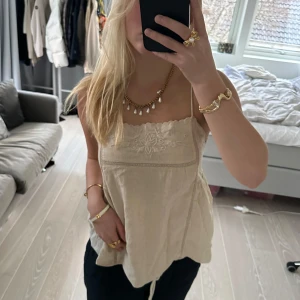 Beige linne med spetsdetaljer - Säljer ett superfint beige linne med tunna axelband och vacker spetsdetalj framtill. Linnet har en lös passform och är tillverkat i ett lätt och bekvämt material. Märket är ZARA och storlek XS. Nypris 379kr