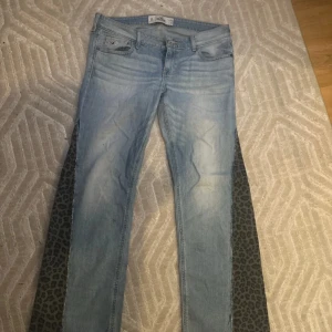 Ljusblå jeans från Hollister - Säljer ett par ljusblå jeans från Hollister i bra skick. då de har blivit förkorta för mig i såna här en och 170 men skulle säga att de passar en person som är runt 165cm. De är utsvängd fit och har en klassisk femficksdesign med knapp och dragkedja, har också väldigt cool detalj med leopard på sidan. Perfekta för vardagsbruk och kan matchas med det mesta i garderoben. Passar både vår och sommar!