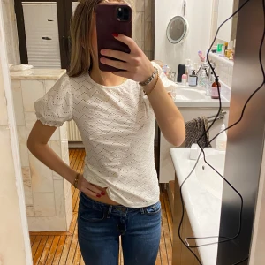 Vit blus med puffärmar - Säljer en superfin vit blus med puffärmar och ett diskret hålmönster. Perfekt för både vardag och fest! Den är i ett mjukt och bekvämt material som känns skönt mot huden. Passar perfekt till jeans eller kjol för en chic look. 💫