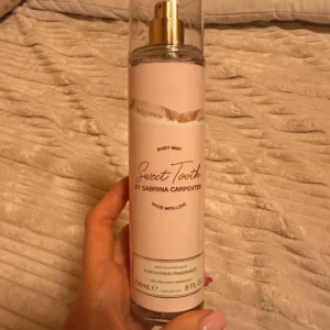 Body Mist Sweet Tooth by Sabrina Carpenter - Säljer en lyxig body mist från Sabrina Carpenter med namnet Sweet Tooth. Flaskan är genomskinlig med en ljusrosa etikett och har en guldig spraypump. Perfekt för att ge en söt och fräsch doft. Innehåller 8 FL OZ (236 mL).
