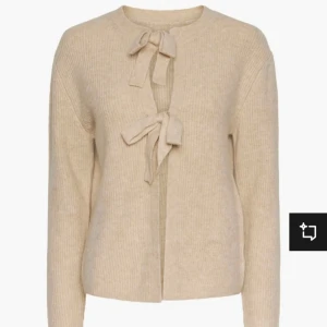 Beige stickad kofta med knyt - Säljer en superfin beige stickad kofta med knyt framtill. Perfekt för höst och vår, den är både mysig och stilren. Koftan har långa ärmar och en normal passform. Passar perfekt till både vardag och fest!