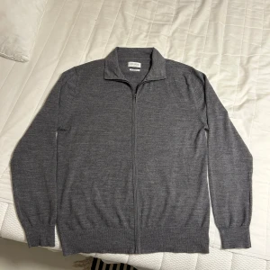Grå fullzip - Säljer denna snygga gråa fullzip från THESE GLORY DAYS. Tröjan är i 100% merino ull och super skön. Mycket bra skick. Nypris 1099kr