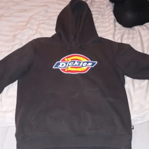 Svart hoodie från Dickies - Säljer en svart hoodie från Dickies i acceptabelt skick. Den har en stor logga på framsidan och är perfekt för höst och vinter. Hoodien är i storlek medium och har en klassisk passform med långa ärmar och en mysig huva. Perfekt för en avslappnad stil!