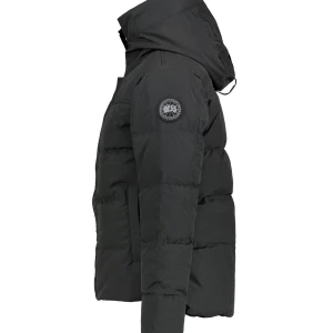 Svart pufferjacka med huva - Säljer en stilren svart pufferjacka från Canada Goose. Jackan har en praktisk huva och ett märke på ärmen. Den är lite använd men den funkar perfekt och den är lite trasig på underdelens sida men man kan knappt se det och det är enklelt art fixa