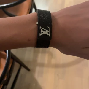 Svart armband med metallspänne - Snyggt svart armband med ett stilrent metallspänne. Perfekt accessoar för att ge en elegant touch till din outfit.