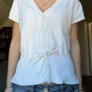Kofta med knytning - Säljer en söt vit stickad kofta med korta ärmar och knappar framtill. Knyts i midjan💗 Står strl L i lappen, men tycker inte de stämmer alls, passar xs-m💗