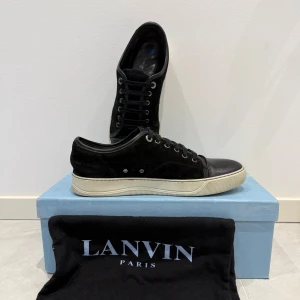 Svarta sneakers från Lanvin - Snygga svarta sneakers från Lanvin med en stilren design. Det är inte med glans på framsidan. Box och duk förs med. Skorna är storlek Uk7 (41-42). De passar mig perfekt och jag har storlek 42,5 på fötterna. 