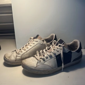 Vita sneakers från Pepe Jeans - Snygga vita sneakers från Pepe Jeans med mörkblå och bruna detaljer. Skorna har snörning och en retrodesign med årtalet 1973 på hälen. Perfekta för en avslappnad stil. Storlek 43 men passar även mindre storlekar. Tveka inte att fråga vid minsta fundering. Priset går att diskuteras