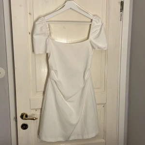 Vit klänning med puffärmar - Säljer en elegant vit klänning med puffärmar med  en öppen rygg från Zara. Prislapp kvar. Aldrig använd. Perfekt till sommaren eller student. Storlek S