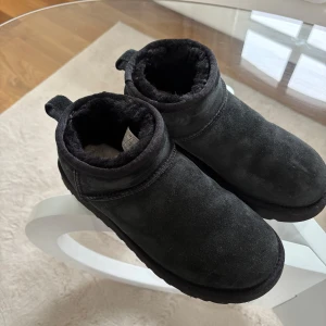 Svarta boots från UGG - Säljer ett par svarta boots från UGG i mocka med mjukt foder inuti. Tror det är ett par ultra mini. Kvitto finns och de är köpta hösten 2022. Sparsamt använda och super fint skick. 700kr