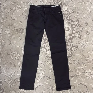 Svarta Replay Hyperflex Anbass jeans - Snygga svarta jeans från Replay i Hyperflex-material för extra komfort och stretch. Modellen är Anbass med en modern passform och klassisk femficksdesign. Perfekta för en stilren look. Alla lappar kvar, passade inte mig tyvärr och fick de i byte mot en annan vara i butik. Nypris: 1600kr. 29 x 32.