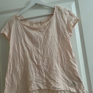 Ljusrosa blus med spetsdetaljer från Odd Molly - Charmig ljusrosa blus från Odd Molly med spetsdetaljer vid nacken och axlarna. Blusen har korta ärmar och en lös passform, perfekt för en avslappnad stil. Den är tillverkad i ett mjukt material som ger en bekväm känsla. Blusen har ett jättefint mönster på ryggen. Den är i fint skick och är sparsamt använd. Vid frågor och funderingar hör av er, jag svarar så fort jag kan!🩷