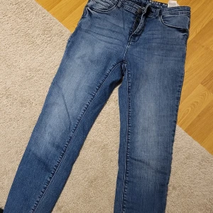 Blå jeans från Noisy May - Snygga blå jeans från Noisy May med dragkedja vid benslut. Perfekta för en casual look med en tight passform. Klassisk femficksdesign och knappgylf.