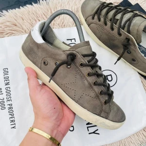 Bruna sneakers från Golden Goose - Snygga bruna sneakers från Golden Goose med vit häl och svarta snören. Skorna har en klassisk design med perforerade detaljer och en robust sula. Perfekta för en avslappnad stil.