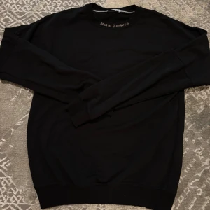 Svart Palm Angels tröja  - Säljer en svart Palm Angels sweatshirt med deras logga tryckt i vitt på baksidan. Tröjan har även loggan på halsringningen.