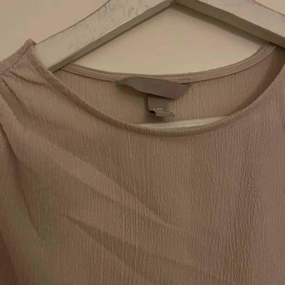 Säljer en stilren beige ärmlös topp från H&M i storlek M. Toppen har en elegant rynkad detalj på sidan som ger en fin passform. Perfekt för både vardag och festliga tillfällen. Materialet är mjukt och bekvämt. Aldrig använd! 💌. Toppar.