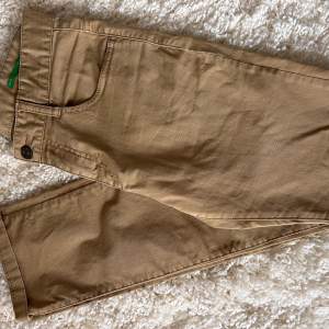 Säljer ett par snygga beige chinos från Benetton i storlek 2XL för barn, 11-12 år. Byxorna har en klassisk design, perfekt för både vardag och lite finare tillfällen. De är i mycket bra skick och stretchmaterial.