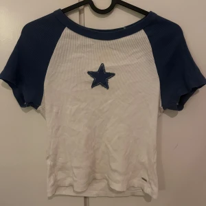 Topp från pull&bear - Säljer en superfin vit och blå ribbad topp med en stjärna på bröstet. Toppen har korta ärmar. Säljer för har knappt används💕💕