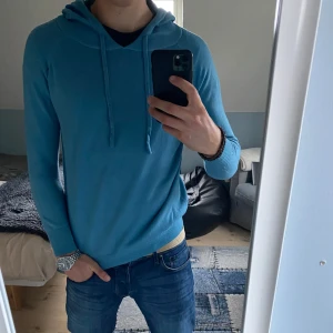 Blå hoodie i bomull - Säljer en snygg blå hoodie i bomull. Den har en normal passform och är perfekt för både vinter och hösten. Skön och stilren utan några defekter. Tveka inte att fråga vid minsta fundering!