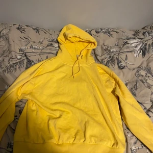 Gul hoodie - Säljer en solgul hoodie i mycket bra skick. Den är perfekt för både vår och höst med sin mjuka och bekväma passform. Hoodien har en klassisk design med dragsko i huvan och ribbade muddar vid ärmslut och nederkant. Perfekt för en avslappnad stil!