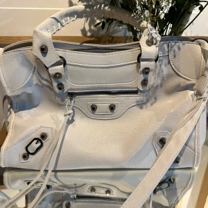Vit handväska med dragkedja - Säljer en snygg vit handväska i PU med coola detaljer. Väskan har en praktisk dragkedja och stiliga metalldetaljer. Perfekt för både vardag och fest! 👜✨