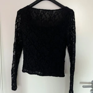 Svart spetsblus - Snygg svart spetsblus med långärmad design. Perfekt för en kväll ute eller en fest. Blusen har ett vackert blommönster och är gjord i ett lätt och luftigt material. Passar bra till både jeans och kjol för en elegant look.