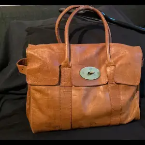 Säljer en snygg brun skinnväska från Mulberry i mycket bra skick. Väskan har ett klassiskt spänne framtill och två handtag. Perfekt för både vardag och fest! 👜