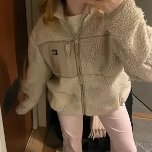 Mysig beige teddyjacka i mycket bra skick. Lik den trendiga som är slutsåld överallt! Perfekt för höst och vinter med dragkedja och en praktisk bröstficka. Jackan har en normal passform och långa ärmar, vilket gör den superbekväm och varm. Perfekt för kalla dagar! Köpt för länge sedan och säljer då jag aldrig använt den. Orginalpriset på jackan är 1100kr 😋 Använder denna i storlek M fast jag själv har Xs! Priset går att diskuteras även!