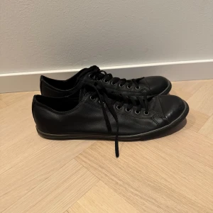 Svarta Converse i skinn - Snygga svarta sneakers i skinn med klassisk snörning från Converse. Perfekta för både vardag och fest. De har en stilren design som passar till det mesta. Skorna är i bra skick och redo för nya äventyr.