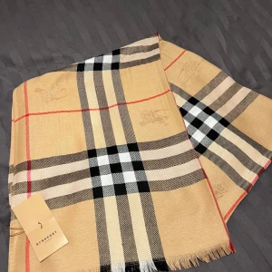 Rutig halsduk från Burberry - Säljer en klassisk rutig halsduk från Burberry i beige⭐️Den har ett stilrent mönster och passar till det mesta. Halsduken är i nytt skick och kommer med originalförpackning. Perfekt för höst och vinter!🍂❄️