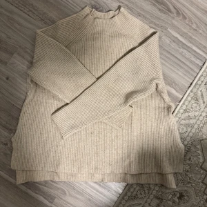 Beige stickad tröja från Amisu - Mysig beige stickad tröja från Amisu i storlek S. Perfekt för kyliga dagar med sin ribbade design och långa ärmar. Tröjan har en klassisk look som passar både till vardags och lite finare tillfällen. Superbekväm och lätt att matcha med andra plagg!