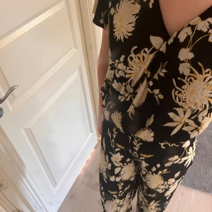Svart blommig jumpsuit - tröja och byxor, luftigt material och inga defekter 
